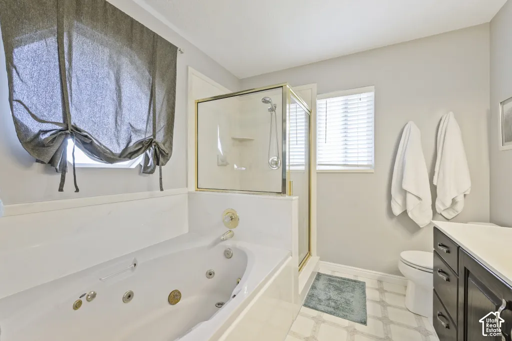 Jetted soaking tub, glass-enclosed shower, dark wood-finish vanity, and a light-toned countertop