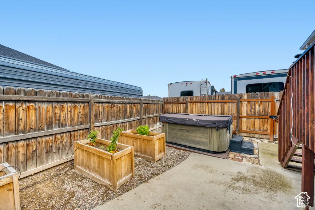 Outdoor space featuring a hot tub, concrete patio, and raised garden beds