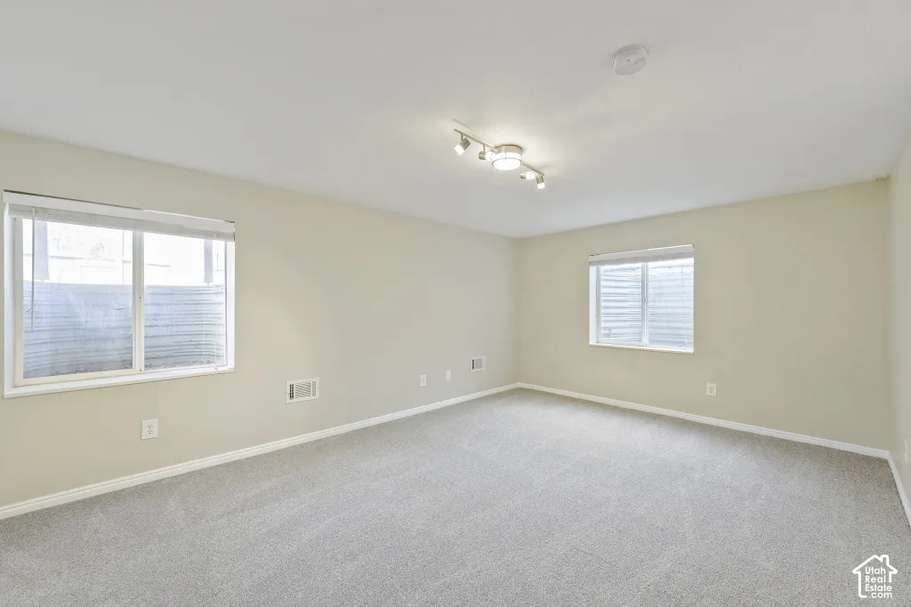 Expansive room featuring light-colored walls, recessed lighting, track lighting, and two windows with blinds