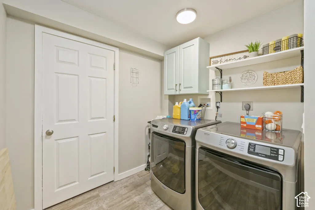 Laundry area featuring overhead cabinetry, wall-mounted shelving, a flush mount light fixture, and wood-finish flooring