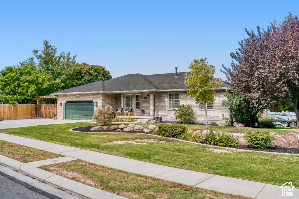 Brick exterior, front porch, attached two-car garage, established landscaping, and a paved driveway