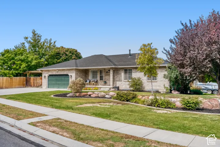 Brick exterior, front porch, attached two-car garage, established landscaping, and a paved driveway
