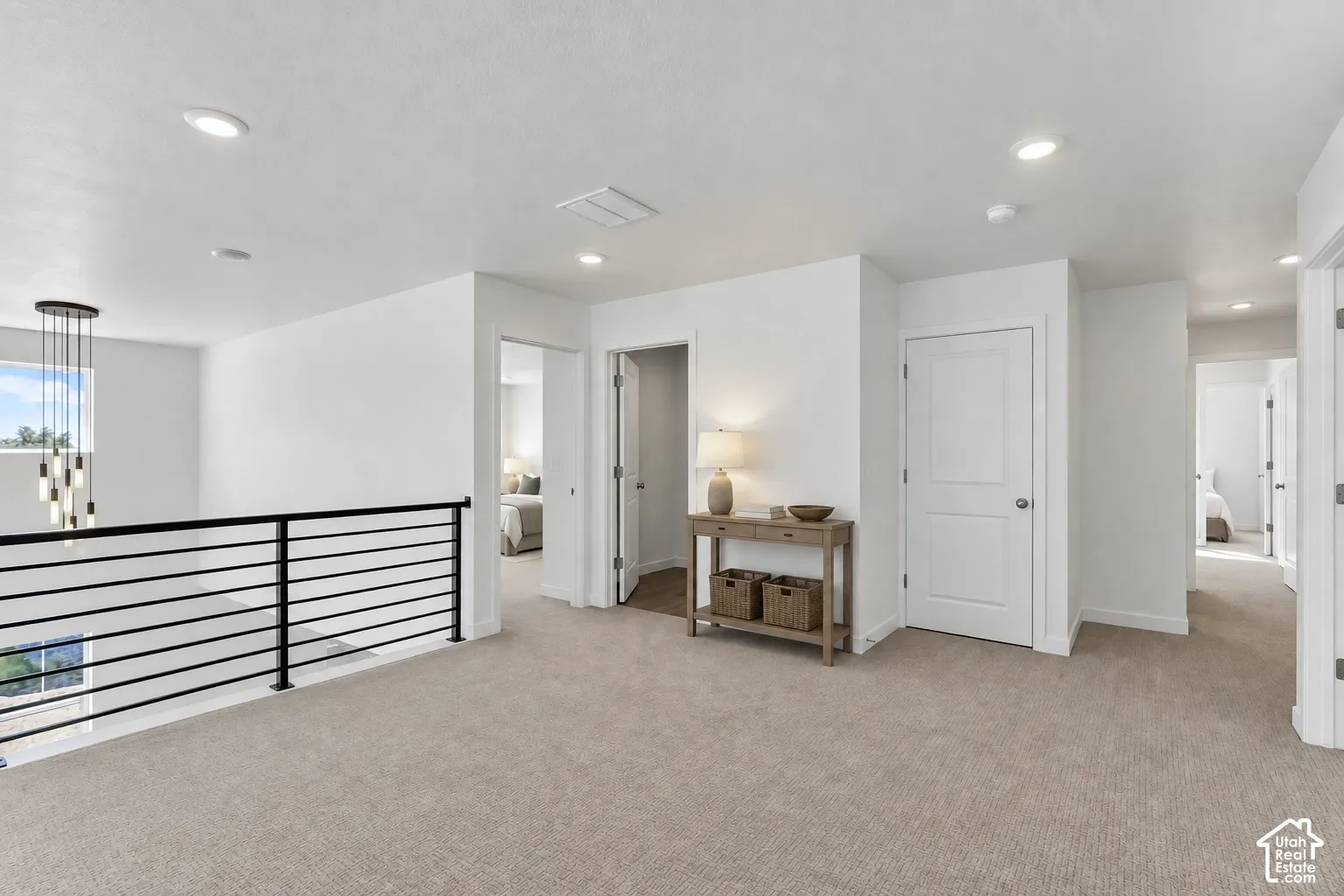 Spacious carpeted loft with recessed lighting, modern linear chandelier, and contemporary black metal railing