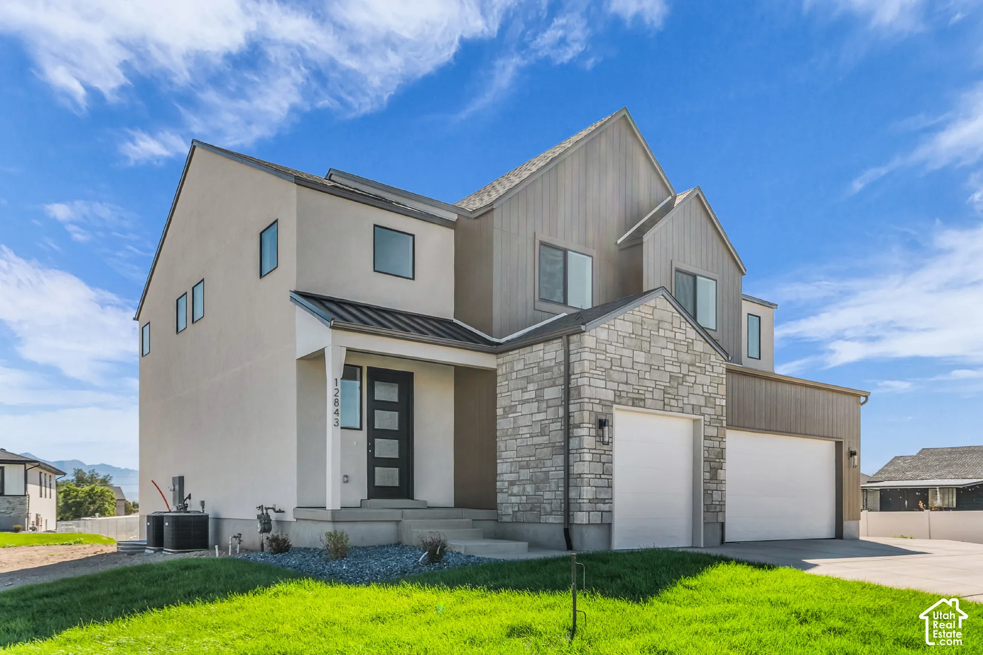 Modern exterior with mixed material siding, stone facade accents, multiple gables, and a two-car garage