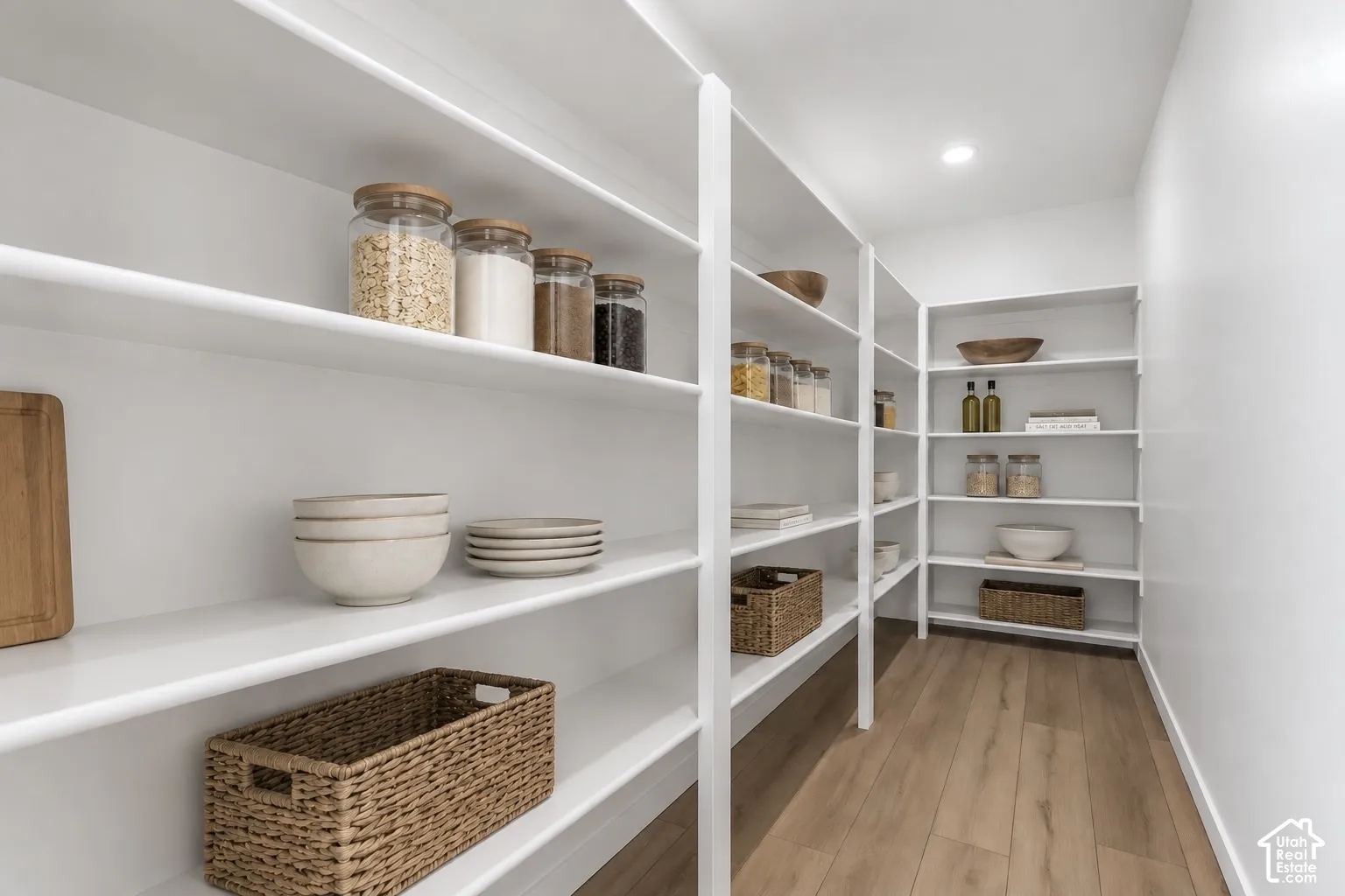 White built-in shelving, recessed ceiling lighting, and wood-finish flooring