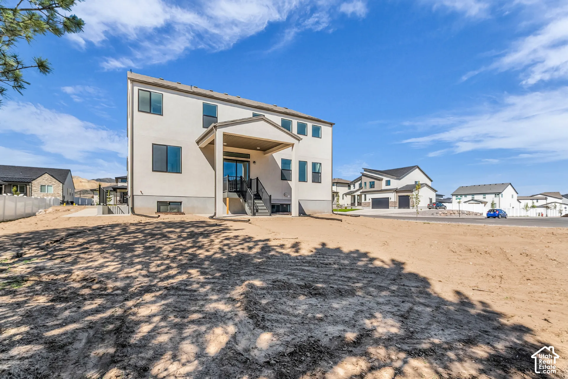 Contemporary stucco exterior with a covered patio, multiple windows, and a walk-out basement entrance