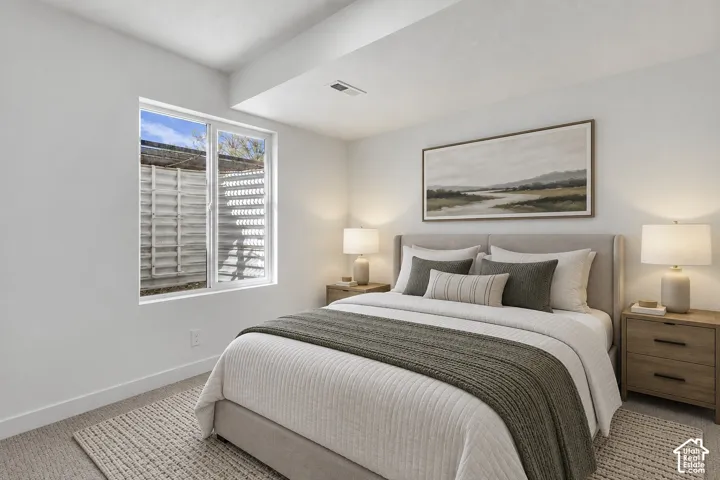 Recessed lighting, wood-finish bedside tables, wall-mounted artwork, and a window with a slatted exterior feature