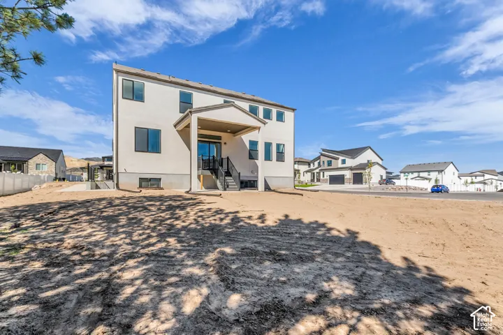 Contemporary stucco exterior with a covered patio, multiple windows, and a walk-out basement entrance