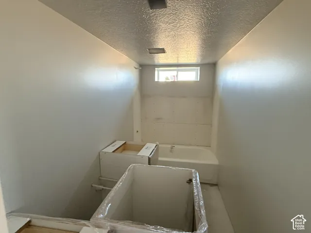 Bathroom space featuring a white soaking tub, an installed unmounted cabinet base, and a horizontal window