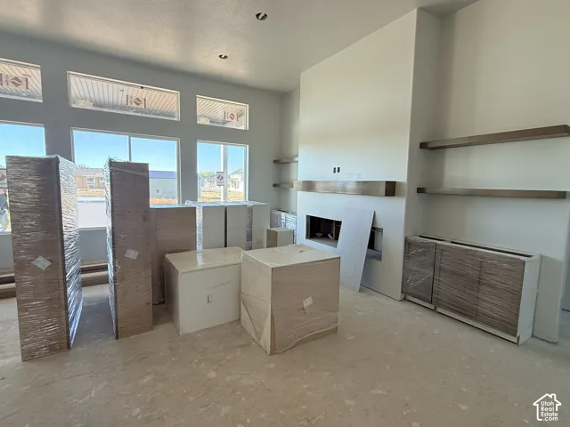 Floor-to-ceiling fireplace with wood mantel, large transom windows, built-in lower cabinetry, and fixed wood-finish wall shelving