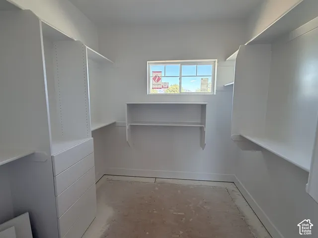 Walk-in closet featuring white built-in shelving, integrated drawer cabinetry, and a horizontal sliding window
