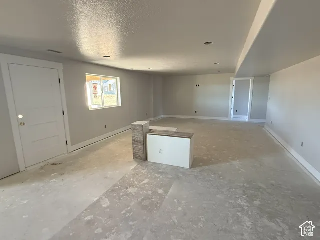 Open-concept interior featuring neutral walls, recessed lighting, a single-panel interior door, and a central built-in island with stone-finish tiling