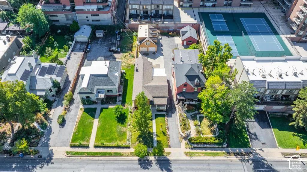Paved driveway, manicured lawn, established trees, and surrounding multi-story buildings