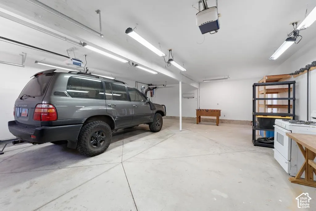Spacious garage featuring concrete flooring and exposed fluorescent lighting