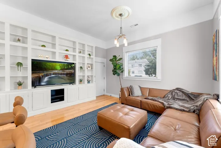 Built-in shelving and cabinetry with media console, hardwood flooring, and a decorative ceiling medallion with a chandelier