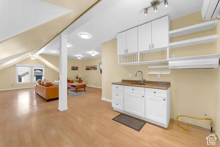 Kitchenette with white cabinetry, stainless steel sink, and wood-finish countertop
