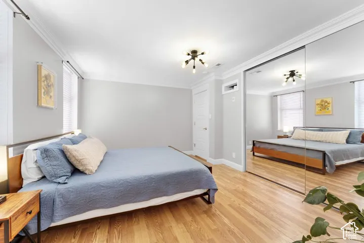 Wood-finish flooring, mirrored closet doors, crown molding, and recessed lighting