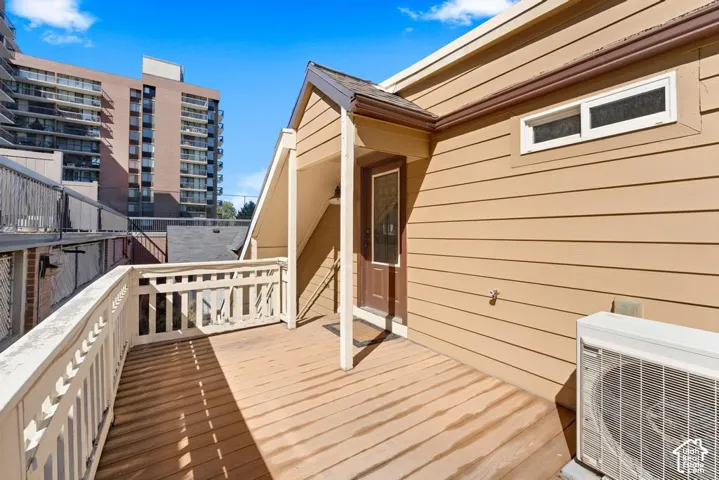 Wooden deck with white railing, tan horizontal siding, and brown entry door