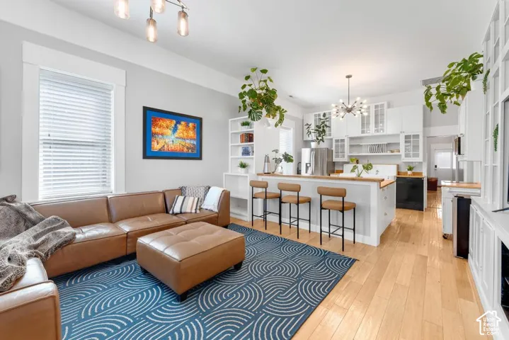 Hardwood flooring throughout, white shaker cabinetry, stainless steel refrigerator, kitchen island with seating, and built-in shelving