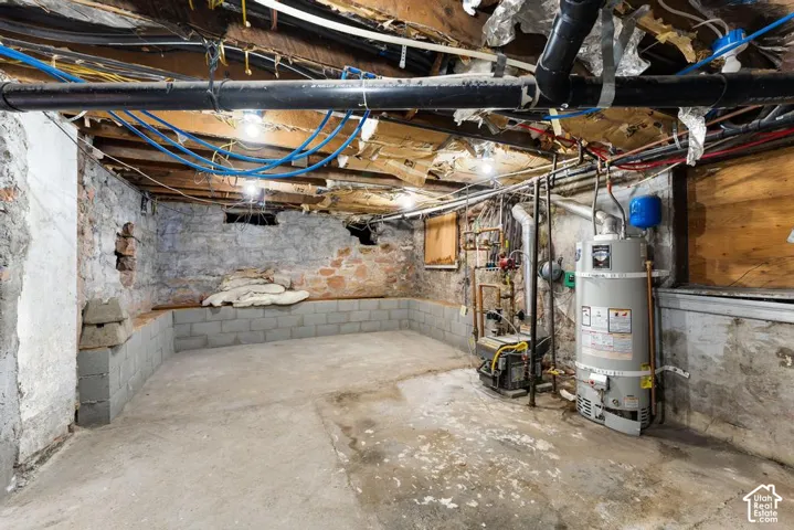 Concrete flooring, concrete block foundation, exposed brick wall, exposed utility piping, and water heater