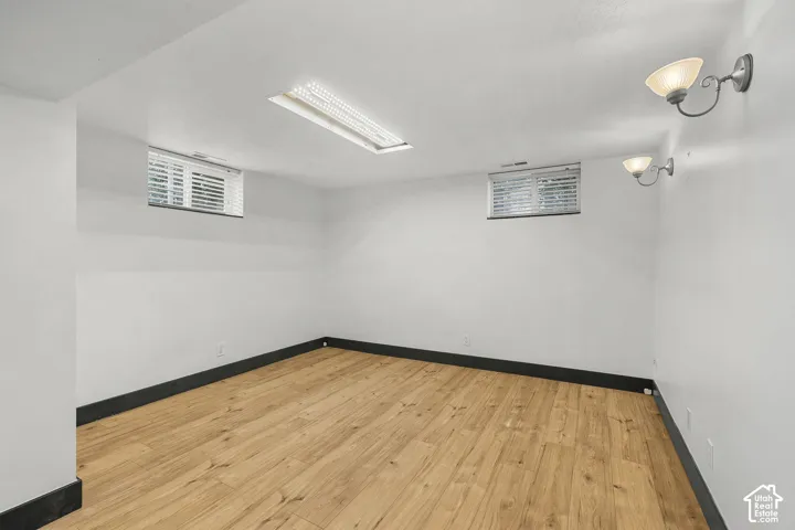 Wood-finish flooring with dark trim, recessed lighting, and dual wall sconces