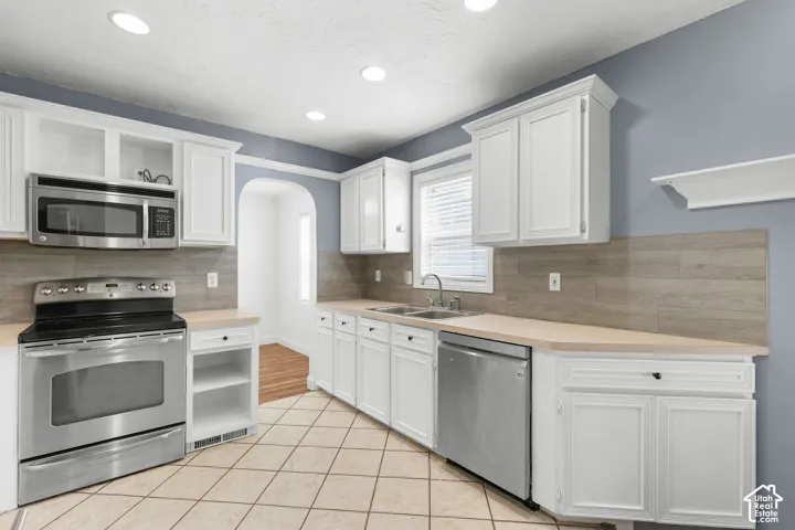 Kitchen featuring white cabinetry, stainless steel appliances, light-toned countertops, tile flooring, and recessed lighting