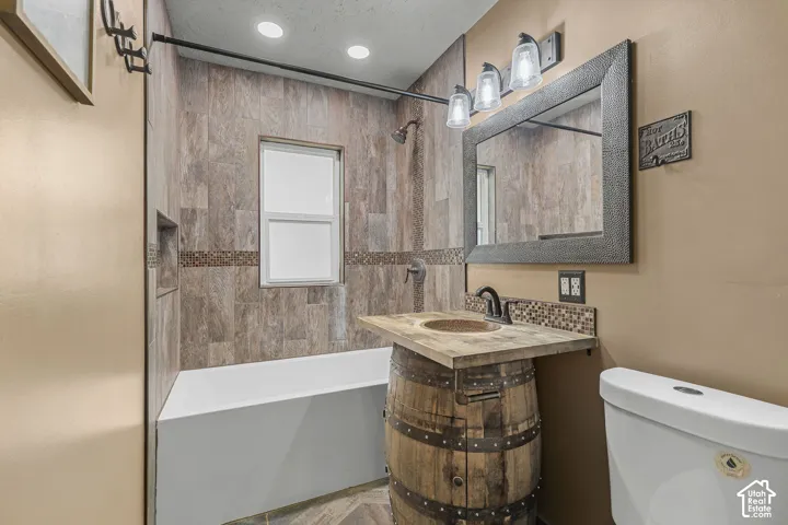 Bathtub with tile surround, built-in shower niche, and an accent tile band