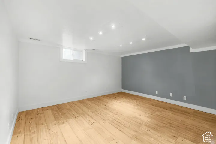 Spacious room featuring wood-finish flooring, recessed lighting, and a window for natural light