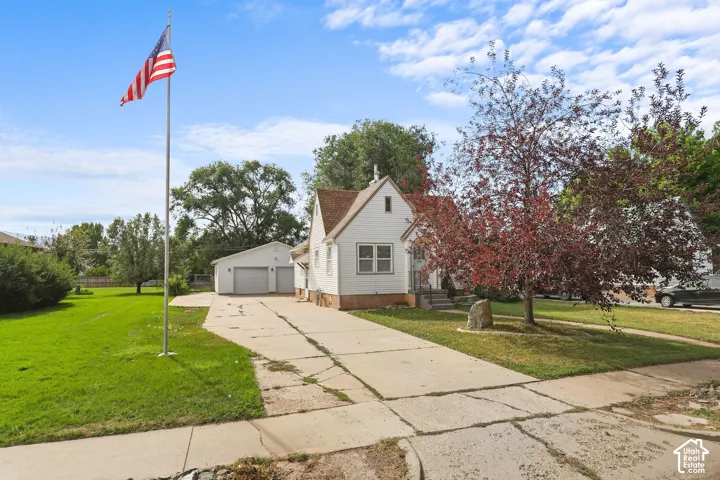 White siding residence with a detached two-car garage, concrete driveway, and a flag pole