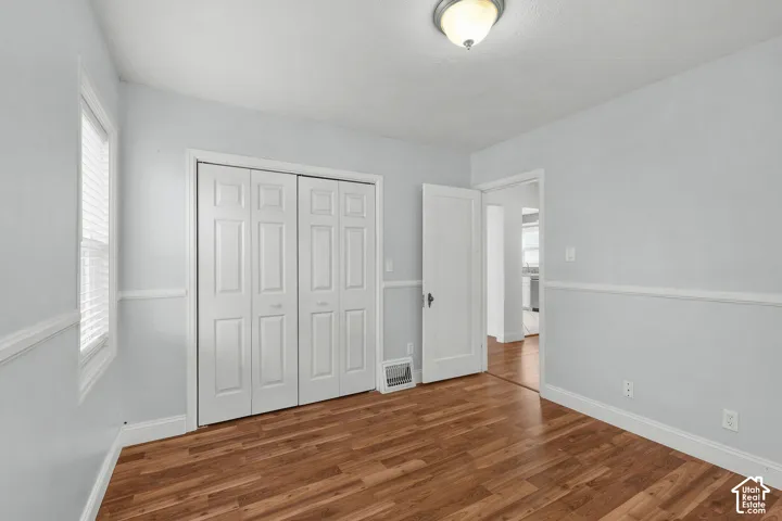 Wood-finish flooring, white bi-fold closet doors, white trim, and a semi-flush mount light fixture
