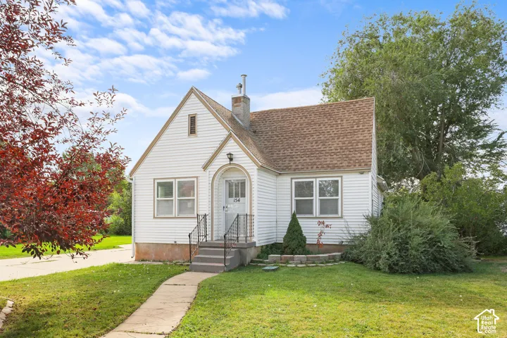 Gable-front home featuring white siding, a shingle roof, and an arched entry