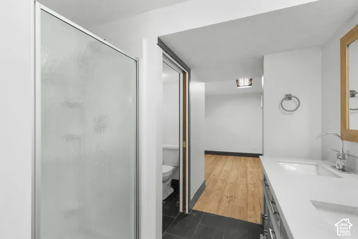 Frosted glass shower enclosure, single vanity with integrated sink, chrome faucet, and a wood-frame mirror