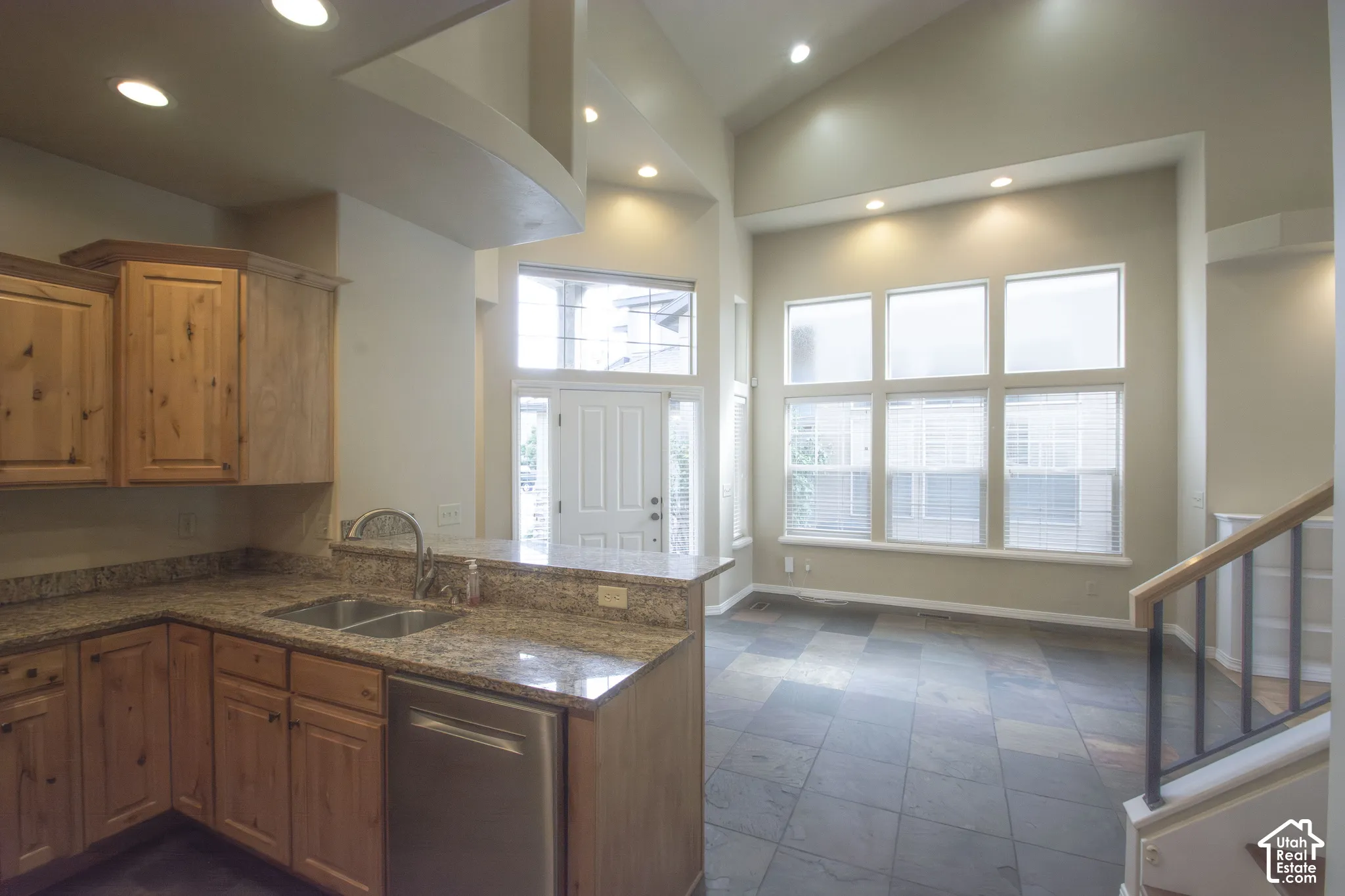 Kitchen featuring wood cabinetry, granite countertops, stainless steel sink, and an integrated dishwasher