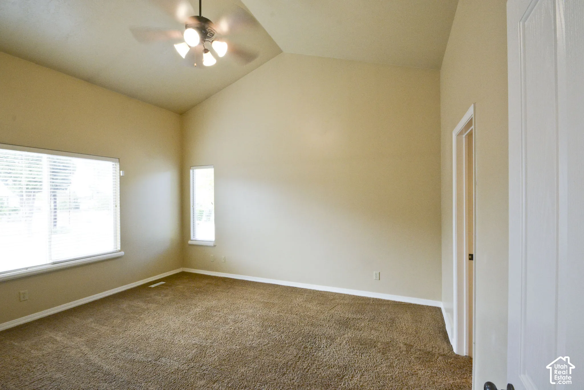 Vaulted ceiling with a ceiling fan, broad window, and a vertical accent window