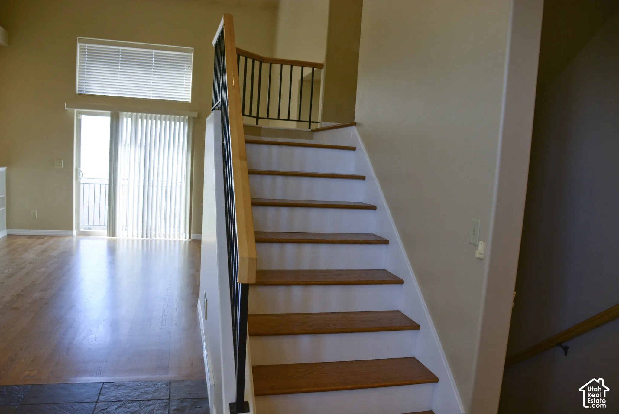 Hardwood flooring, wood tread staircase with contrasting risers, and wrought iron balusters
