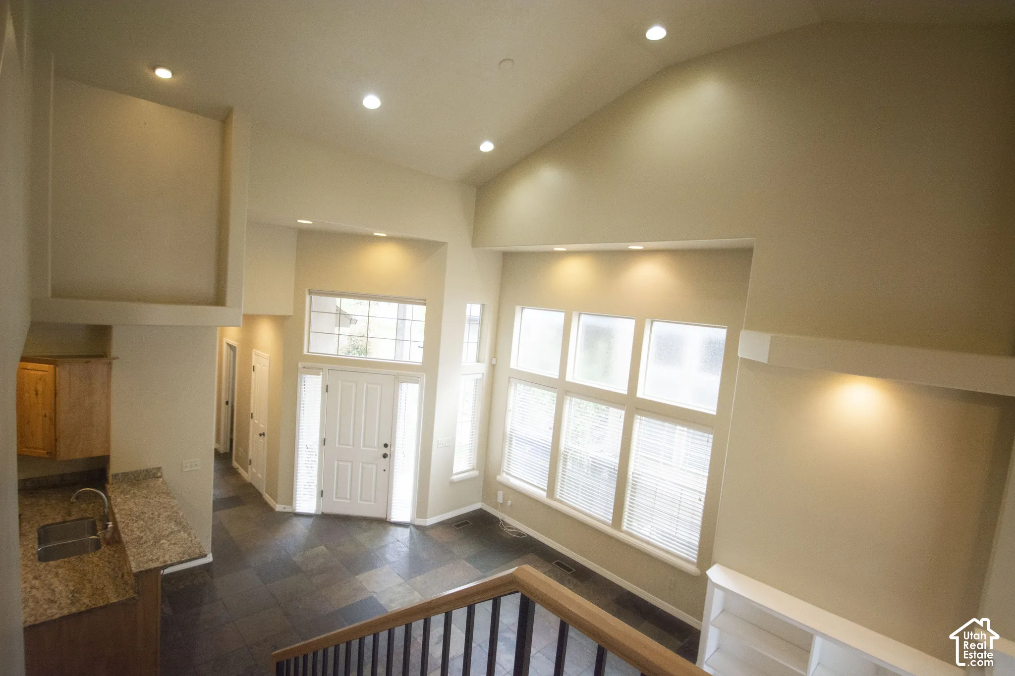 Vaulted ceilings, recessed lighting, and large windows illuminate the entry
