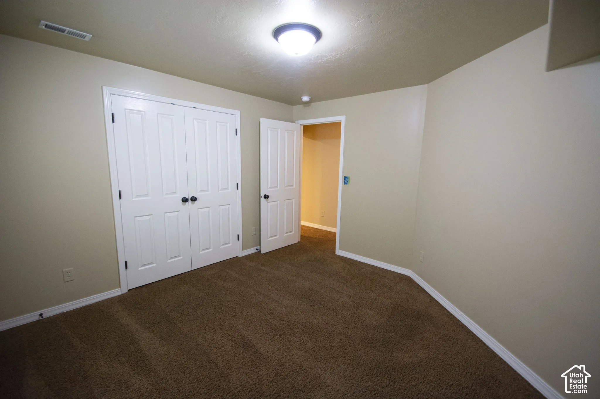 Neutral wall finishes, recessed ceiling light, and brown carpet flooring