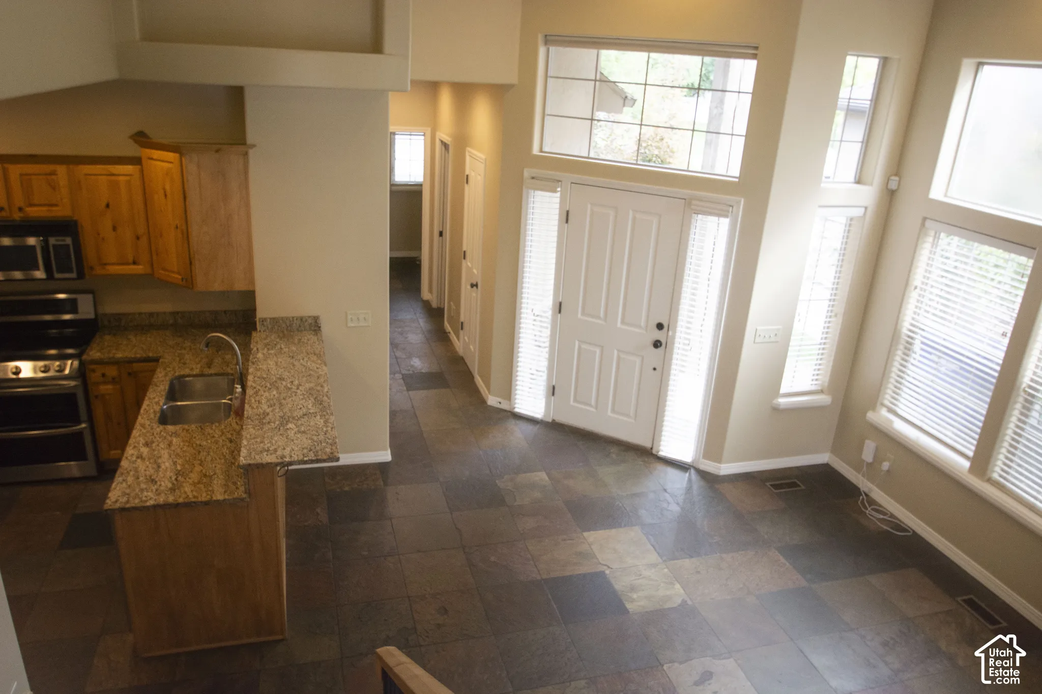 Entry with slate tile flooring, two-story ceiling, and abundant natural light
