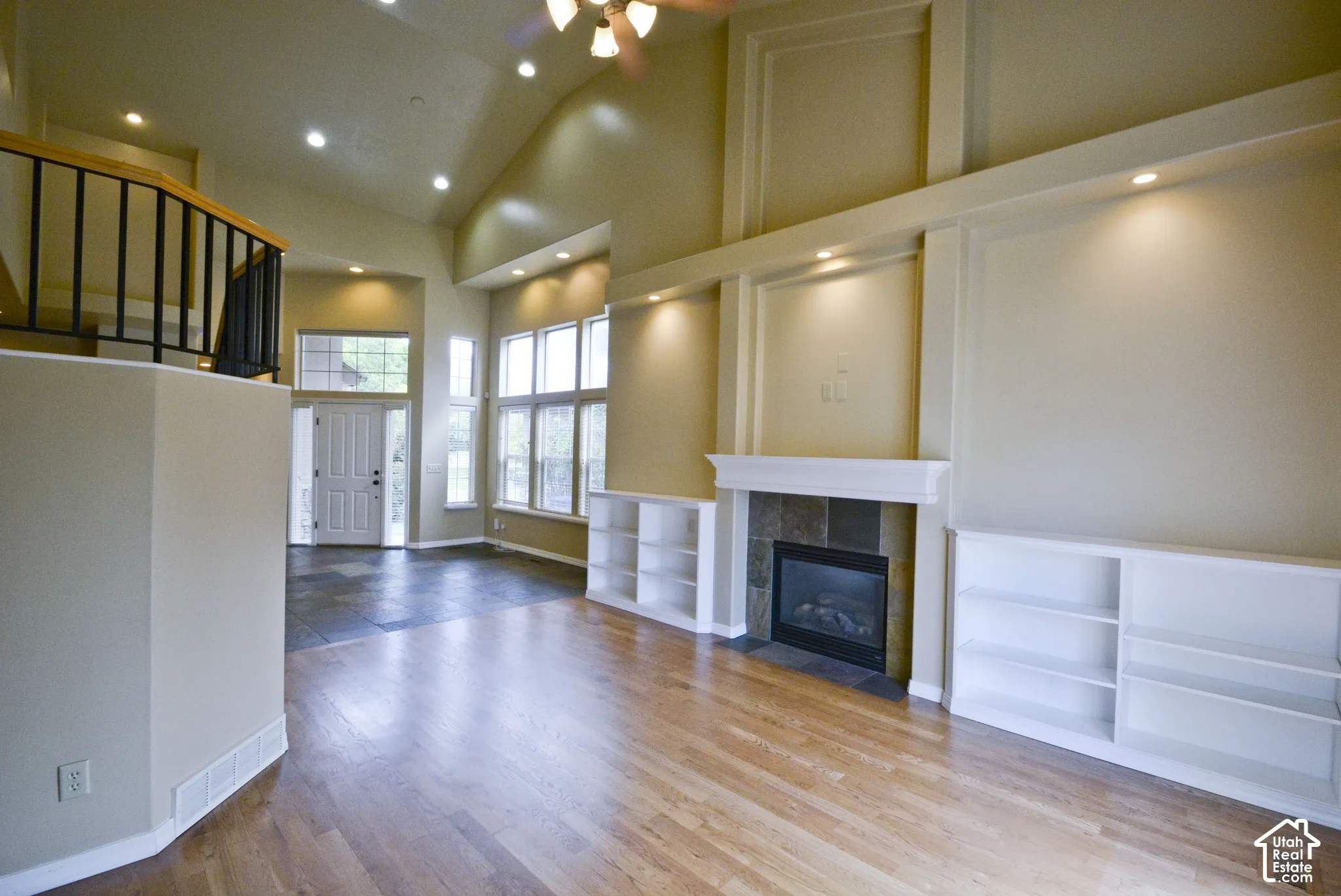Vaulted ceiling, wood-finish flooring, built-in shelving, tile-surround fireplace, and an abundance of natural light