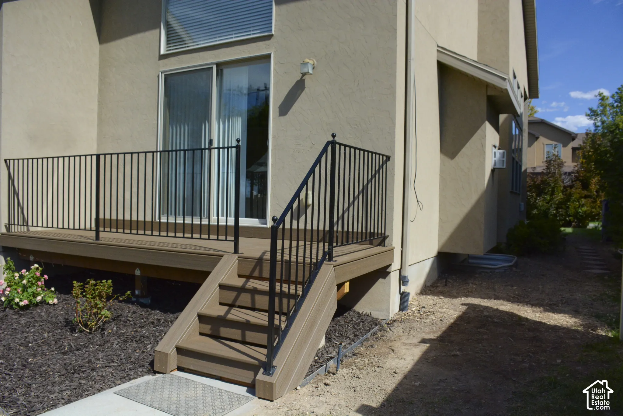 Exterior deck with composite decking, black metal railing, and direct access through a sliding glass door
