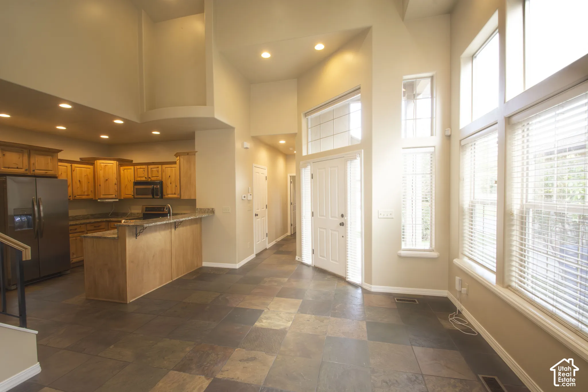 Vaulted ceilings with recessed lighting, large format tile flooring, and abundant natural light