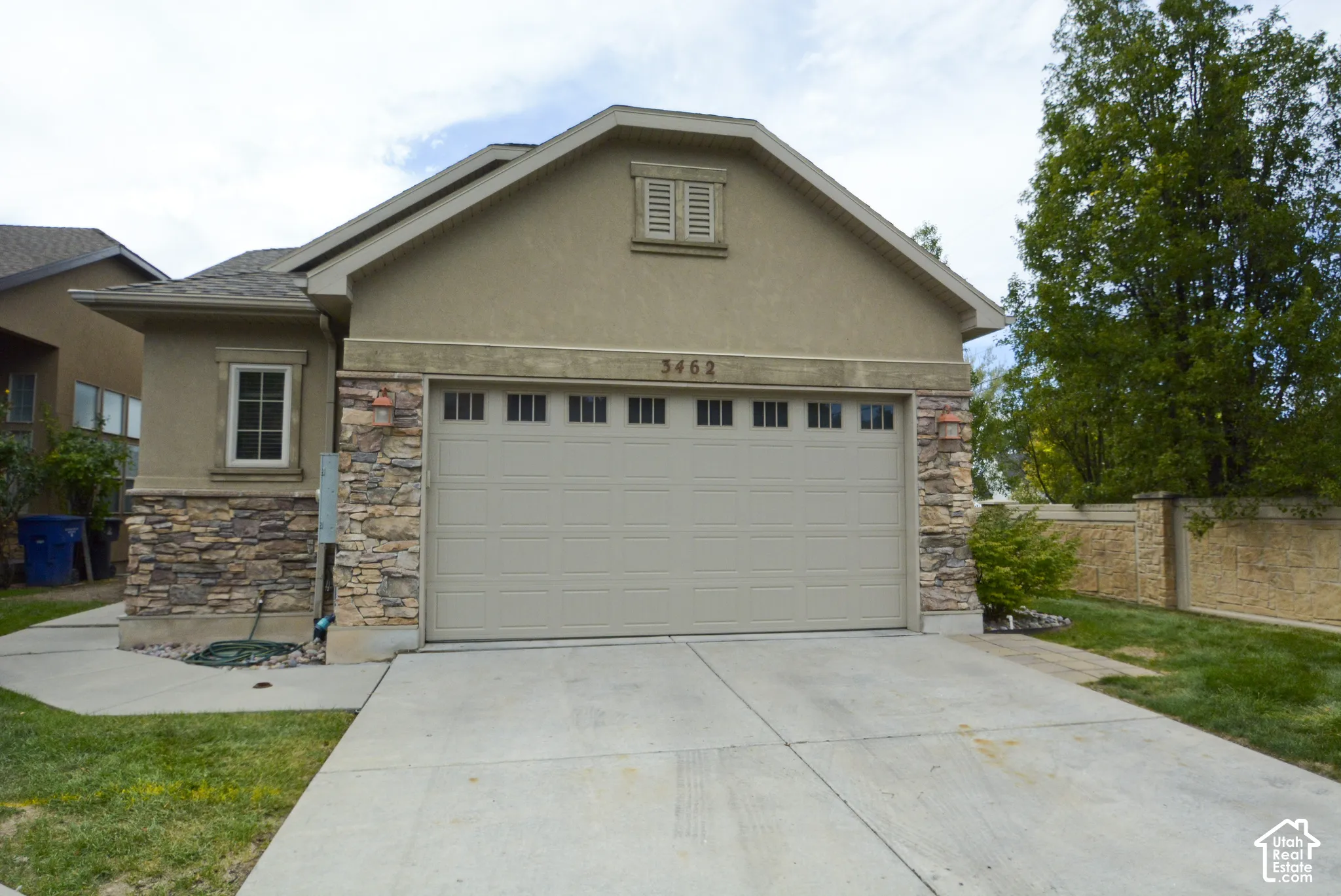 Stucco exterior with stone accents, a two-car garage, and a concrete driveway