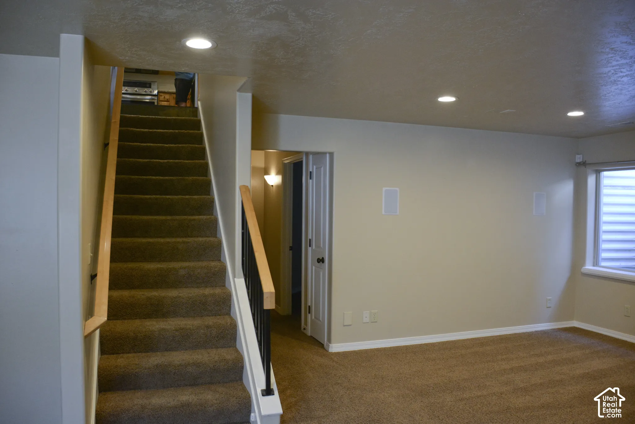 Carpeted staircase with wood-finish handrails and black metal balusters