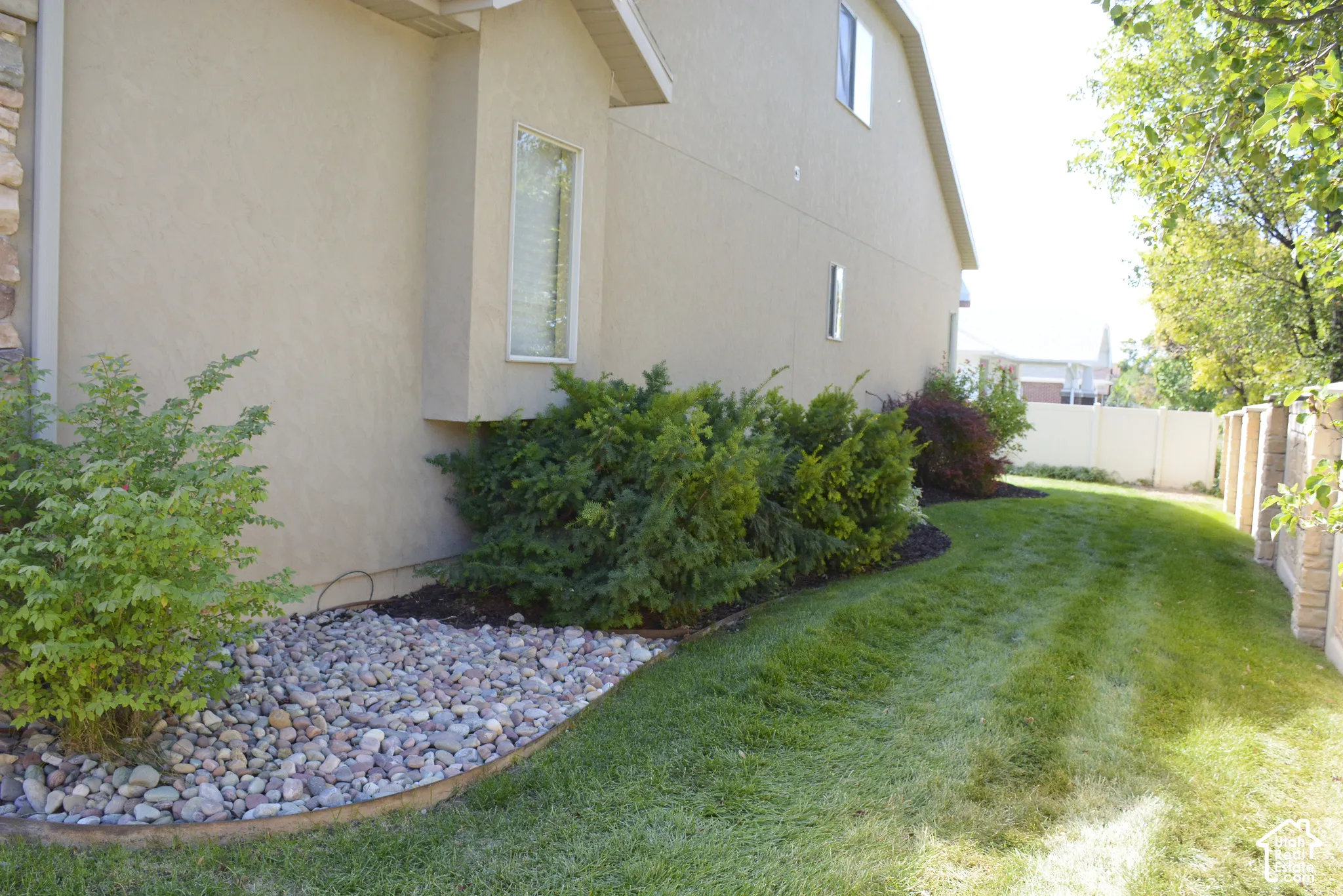 Stucco exterior with stone accenting, bay window, landscaped rock bed, and established shrubbery