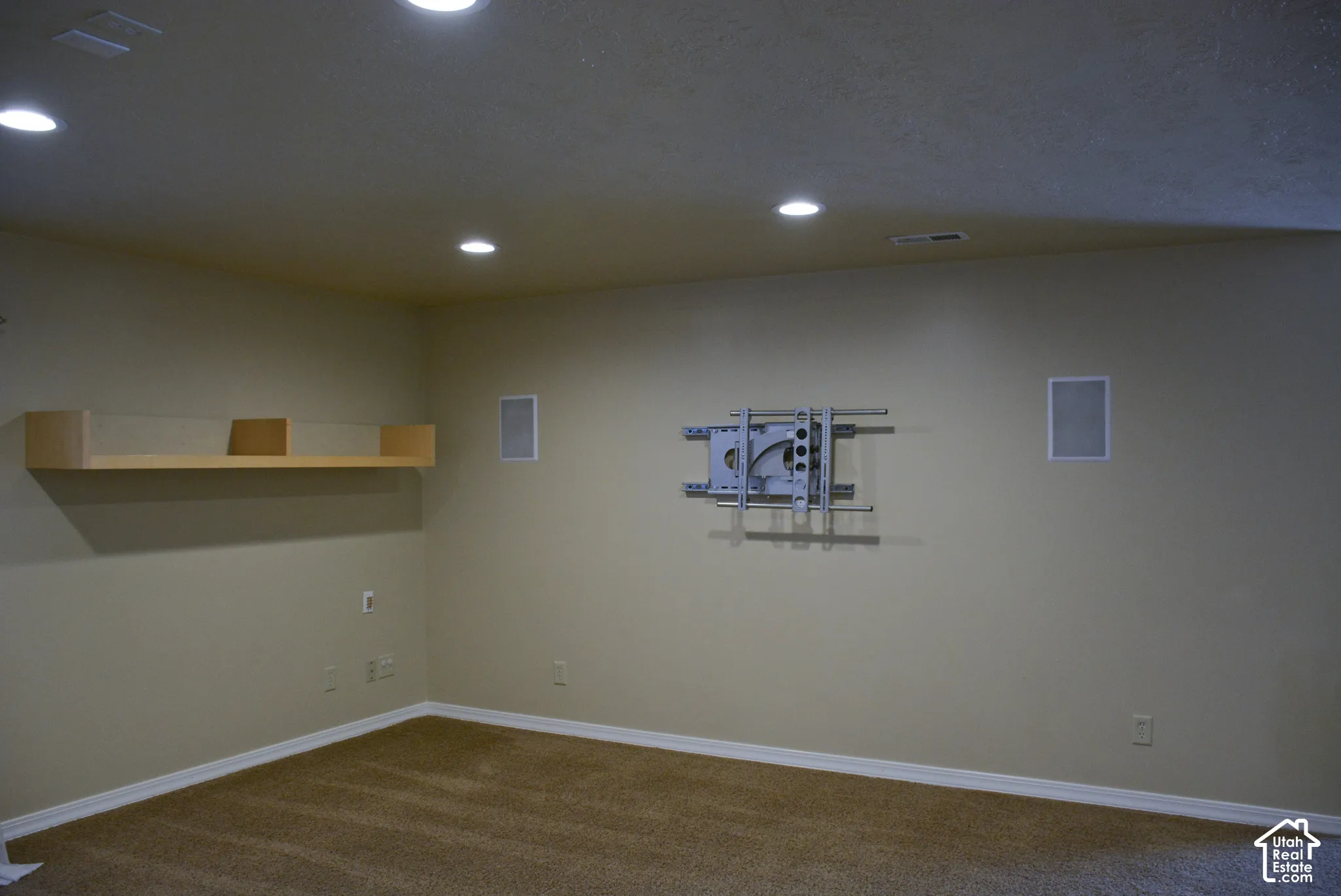 Recessed ceiling lighting, built-in wall speakers, wall-mounted shelving, and a pre-installed TV mount