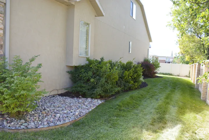 Stucco exterior with stone accenting, bay window, landscaped rock bed, and established shrubbery