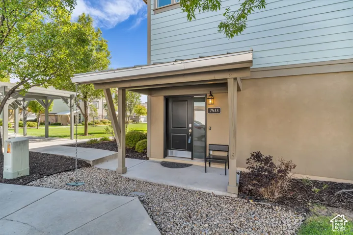 Covered entryway with overhead lighting, concrete walkway, and gravel landscaping