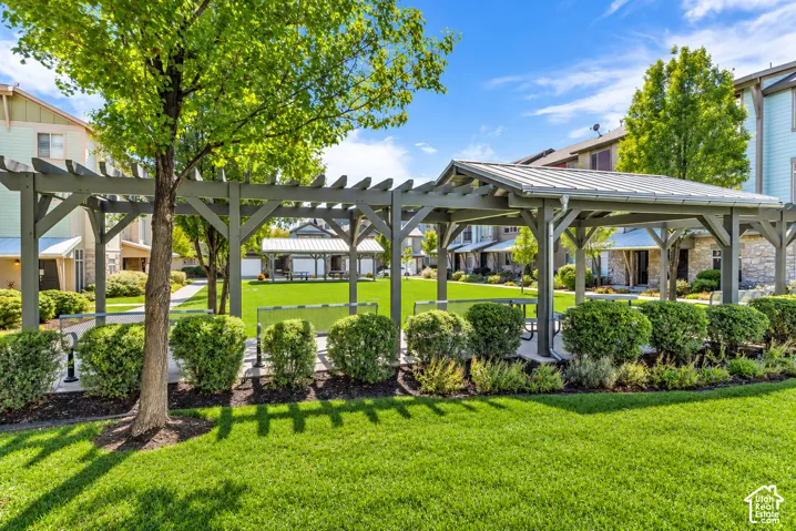 Manicured lawn with a large wooden pergola, mature trees, and established shrubbery