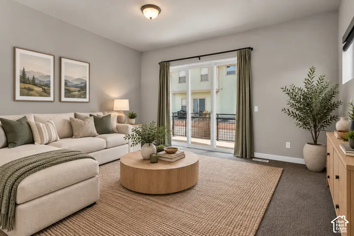 Carpeted living area with light gray walls, a built-in light fixture, and sliding glass doors with a black frame