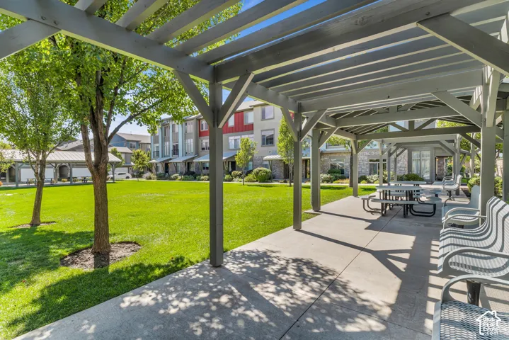 Expansive outdoor pavilion featuring a large green space, mature trees, and concrete pathways